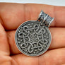 Silver Replica pendant with intricate design held in a hand