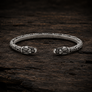Open Viking dragon head armring in Italian silver-plated bronze with Norse-inspired detailing on dark rustic wood.
