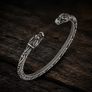 Open Viking dragon head armring in Italian silver-plated bronze with Norse-inspired detailing on dark rustic wood.