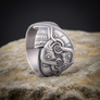 Silver Raven ring with intricate design on a stone surface