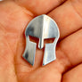 Silver Spartan helmet pendant held in a hand