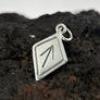 Silver Tiwaz pendant with a geometric design on a dark, textured surface
