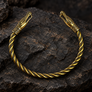 Viking Urnes dragon head brass armring on dark rugged stone
