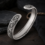 Jelling style sterling silver Viking armring on dark wood surface