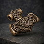Angled side view of bronze Mjolnir pendant highlighting its carved Norse details and antiqued finish