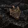 Bronze Fenrir wolf pendant with Norse knotwork, angled view on dark stone