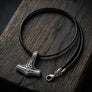Triquetra Thor’s Hammer silver pendant with a smooth black leather cord arranged on dark wood