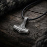 Angled view of Triquetra Mjolnir pendant in 925 sterling silver on dark wood