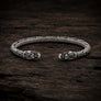 Open Viking dragon head armring in Italian silver-plated bronze with Norse-inspired detailing on dark rustic wood.