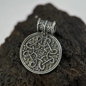Silver Birka pendant with intricate design on a dark, textured surface