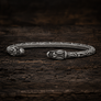 Open Viking dragon head armring in Italian silver-plated bronze with Norse-inspired detailing on dark rustic wood.