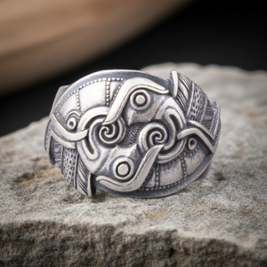 Silver Raven ring with intricate designs on a stone surface