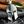 Silver Spartan helmet pendant on a dark surface with wooden and leaf background