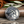 Silver Spartan pendant with a detailed design on a reflective surface with leaves in the background