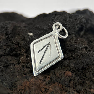 Silver Tiwaz pendant with a geometric design on a dark, textured surface