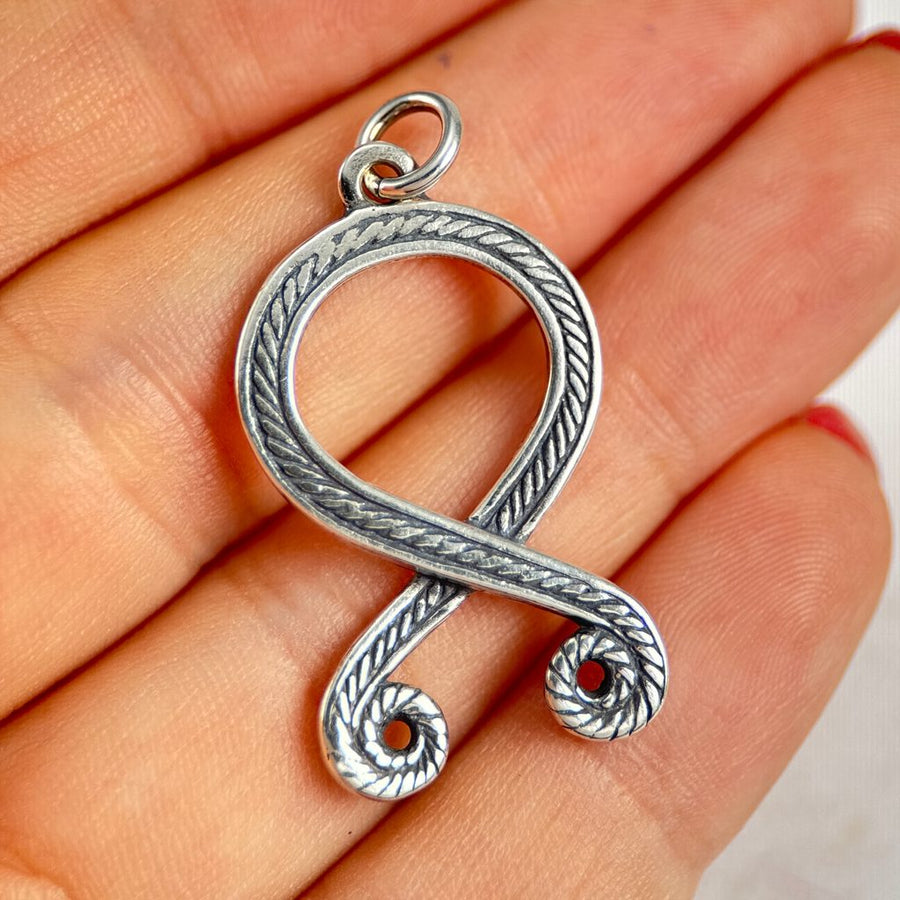 Silver Troll Cross pendant shaped like a question mark held in a hand