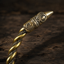 A close-up of a decorative bronze raven head of an armring, resting on a dark rustic wooden surface.
