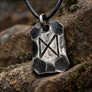 Dagaz rune steel pendant displayed on natural stone