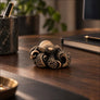 Octopus bronze figurine displayed on a dark wooden desk in a moody studio setting