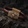 Skoll and Hati Viking bracelet in bronze and leather photographed at an angled view on black stone