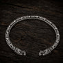 Open Viking dragon head armring in Italian silver-plated bronze with Norse-inspired detailing on dark rustic wood.