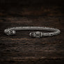 Open Viking dragon head armring in Italian silver-plated bronze with Norse-inspired detailing on dark rustic wood.